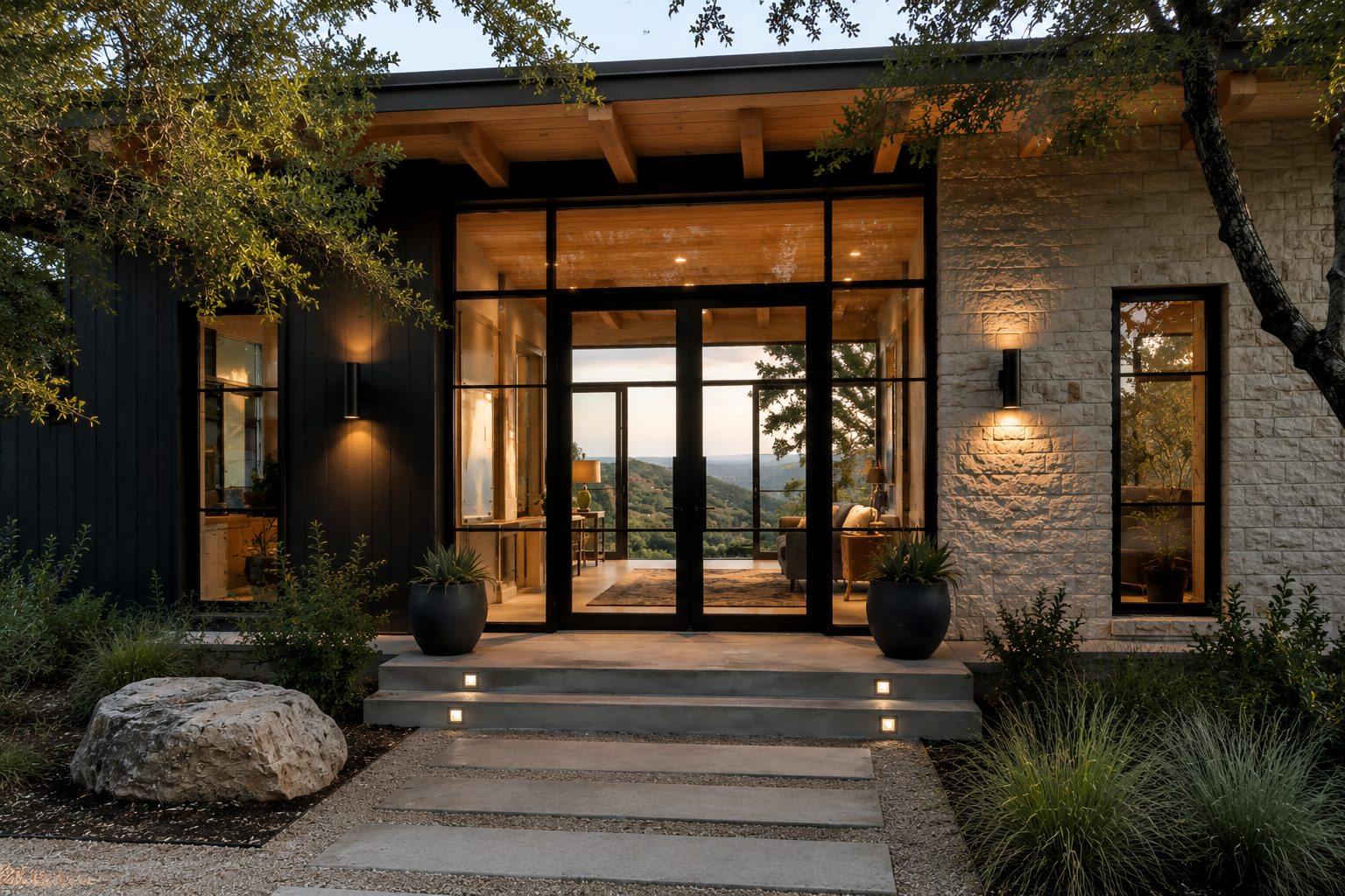 Hill Country home with black steel-frame glass entry at dusk